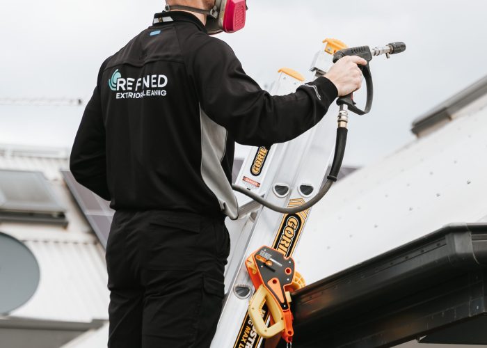 Roof cleaning service with a technician using safe equipment to remove dirt, moss, and debris from a roof.