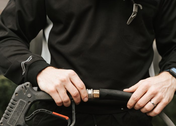 Refined Exterior Cleaning Technician using a soft washing technique to clean the exterior of a building, ensuring a gentle, effective clean